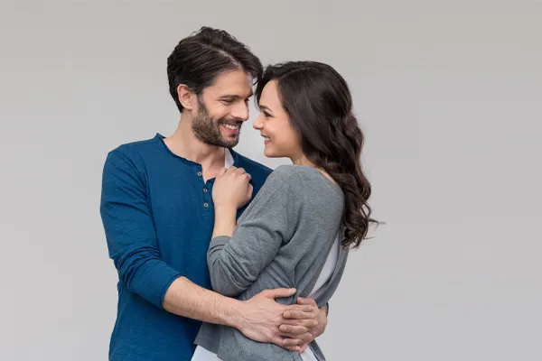 Erectile-Dysfunction-Doctor A man in a blue shirt embracing a woman in a gray shirt smiles due to his successful erectile dysfunction care from Raving Health in Virginia Beach.