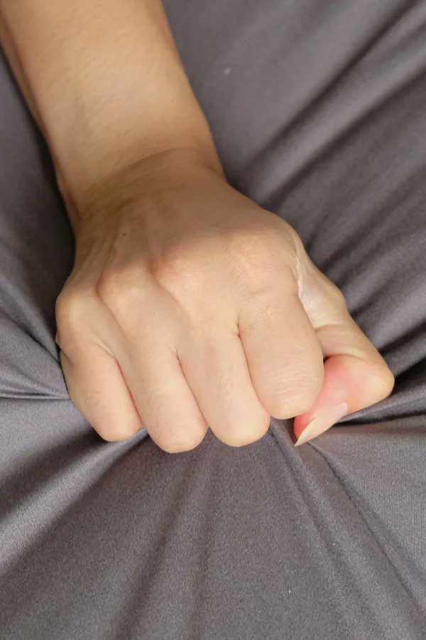 Close-up of a woman's hand grabbing a sheet, indicating sexual pleasure. Get female sexual dysfunction treatment from Raving Health in Virginia Beach.