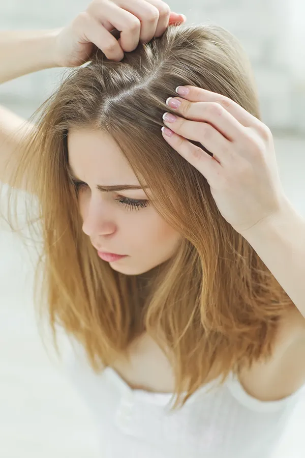 Hair-Restoration-Treatment A woman inspects the part in her long brown hair, worried about hair loss. Get Nutrafol treatments from Raving Health in Virginia Beach.