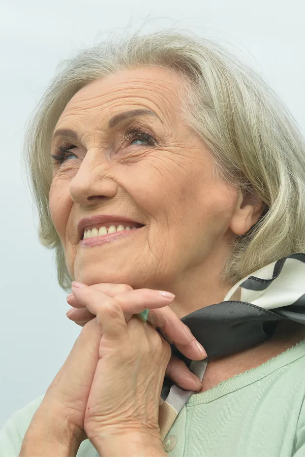 Hot-Flashes-and-Night-Sweats-Treatments An older woman holds her hands together under her chin and looks up at a cool sky smiling. Get treatment for hot flashes and night sweats from Raving Health in Virginia Beach.