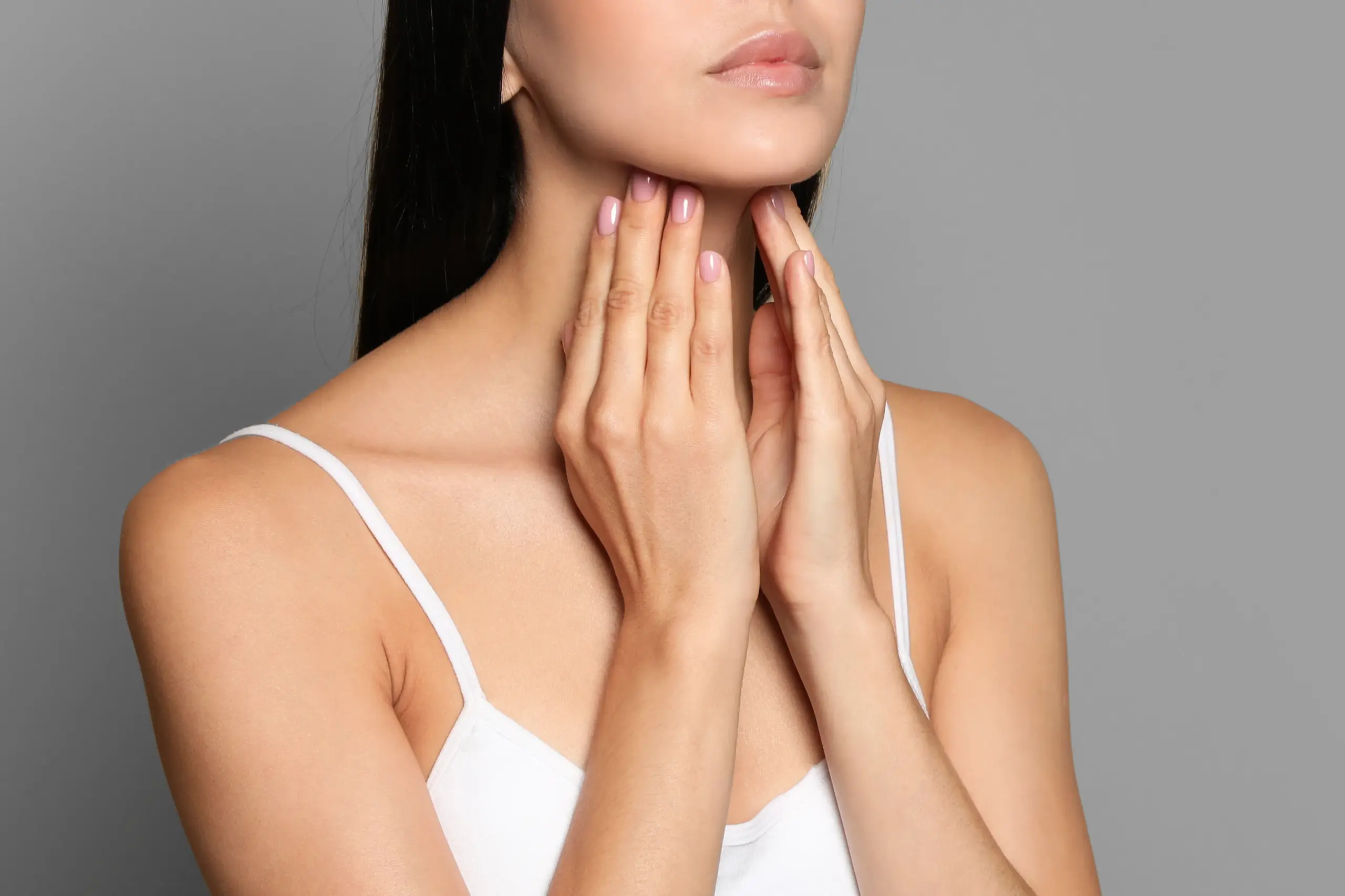 Thyroid-Doctor A woman in a white tank top touches her neck looking for signs of thyroid disorder. Get help for thyroid disorders from Raving Health in Virginia Beach.